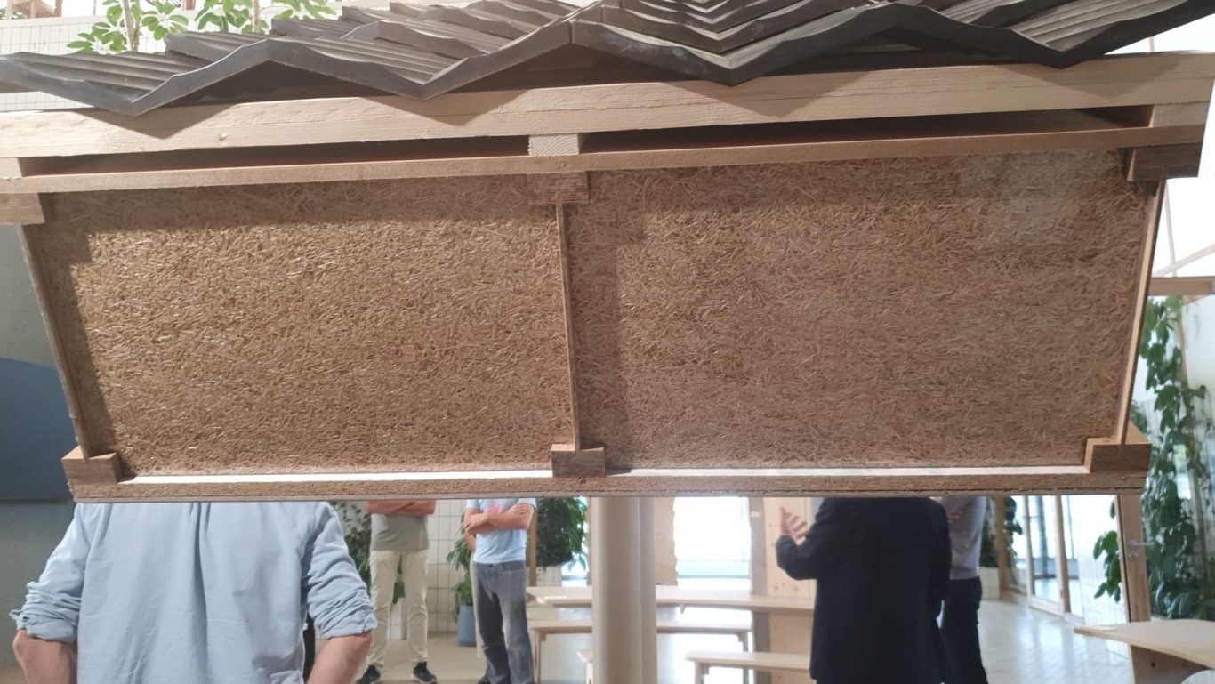 Vooraanzicht van een dakelement met BAS I-liggers, zichtbare vezelisolatie tussen de profielen en zwarte dakpannen.