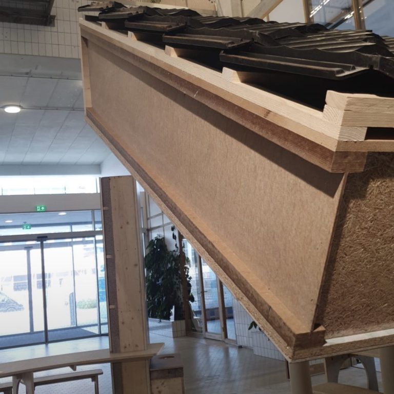 Dakelement met BAS I-liggers Demonstratiemodel van een dakelement met BAS I-liggers, zichtbare vezelisolatie en zwarte dakpannen.